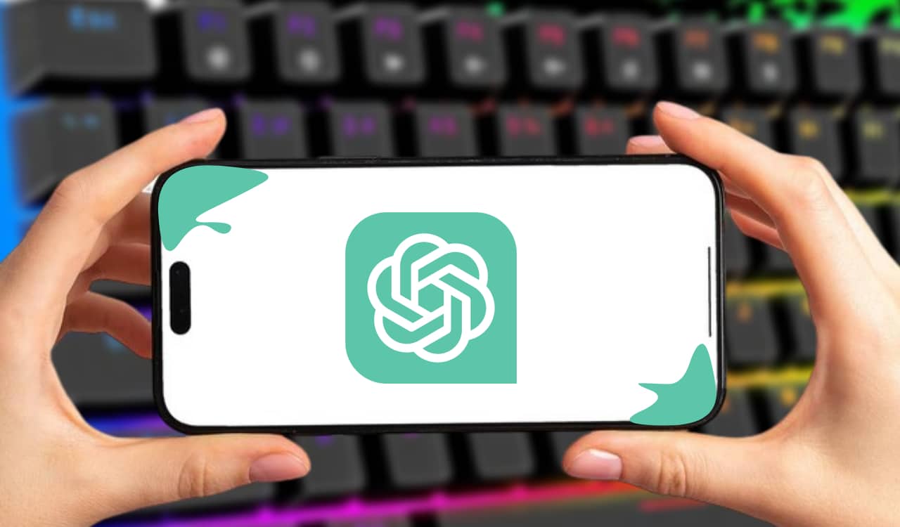 Mão segurando um celular com o logotipo do ChatGPT na tela e um teclado de computador neon ao fundo