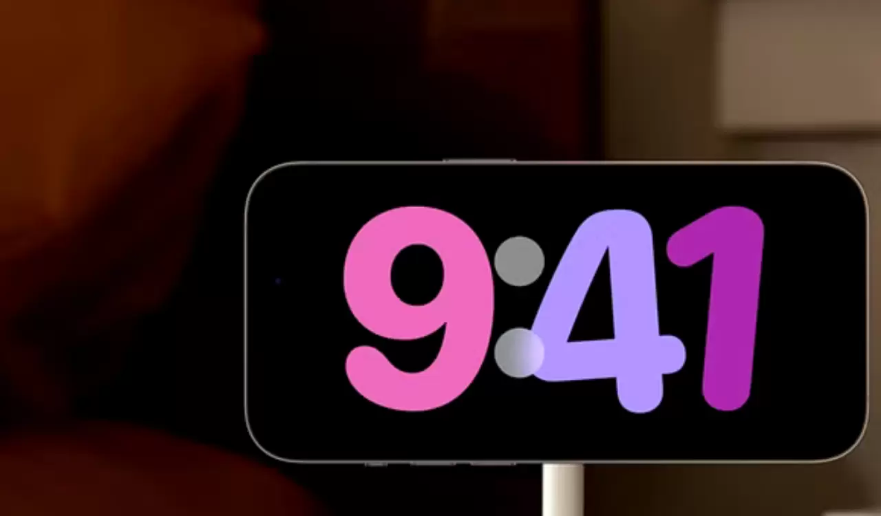 Um iPhone em uma mesa de cabeceira com modo Standby ativado com um relógio colorido